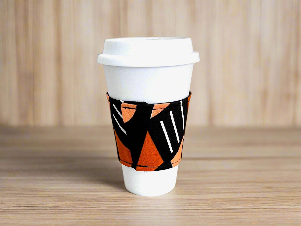 Handmade Cup Sleeve: Ethnic fabric design in black, orange, and white. This vibrant and stylish mud cloth inspiredcup sleeve adds a touch of cultural sophistication to your drinkware.