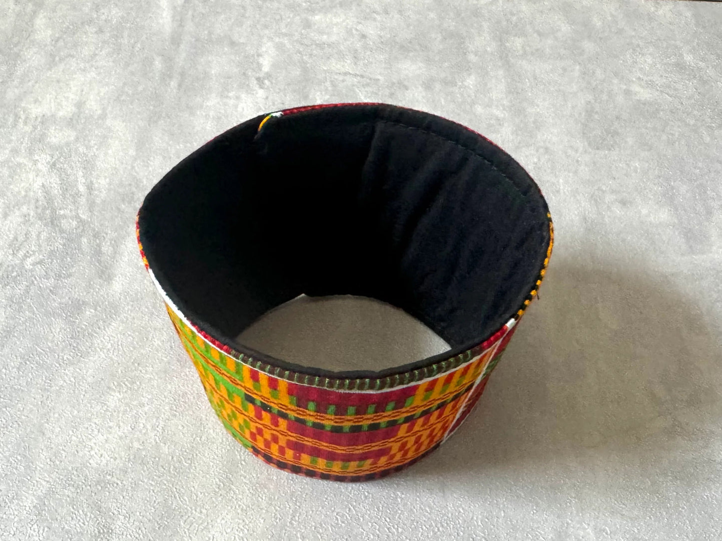 Handmade Cup Sleeve: Ethnic fabric design in Handmade Cup Sleeve: Ethnic fabric design in orange, red, green, black, and yellow. This vibrant and stylish cup sleeve adds a touch of cultural sophistication to your gift giving.